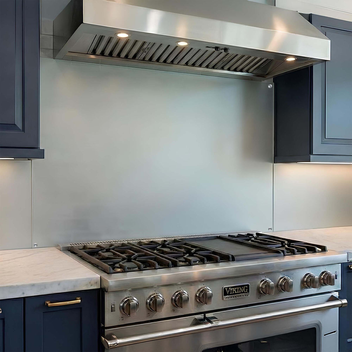 Stainless steel Viking range with hood and glass backsplash in a modern kitchen