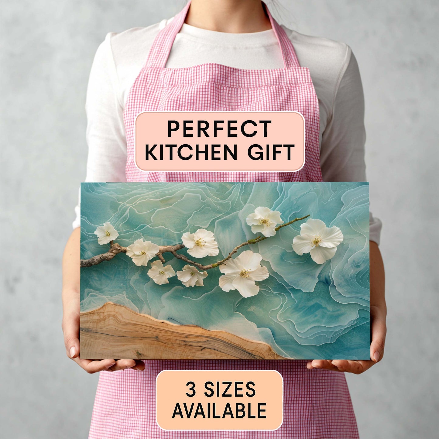 Person holding a decorative cutting board with floral design and text about it being a perfect kitchen gift.