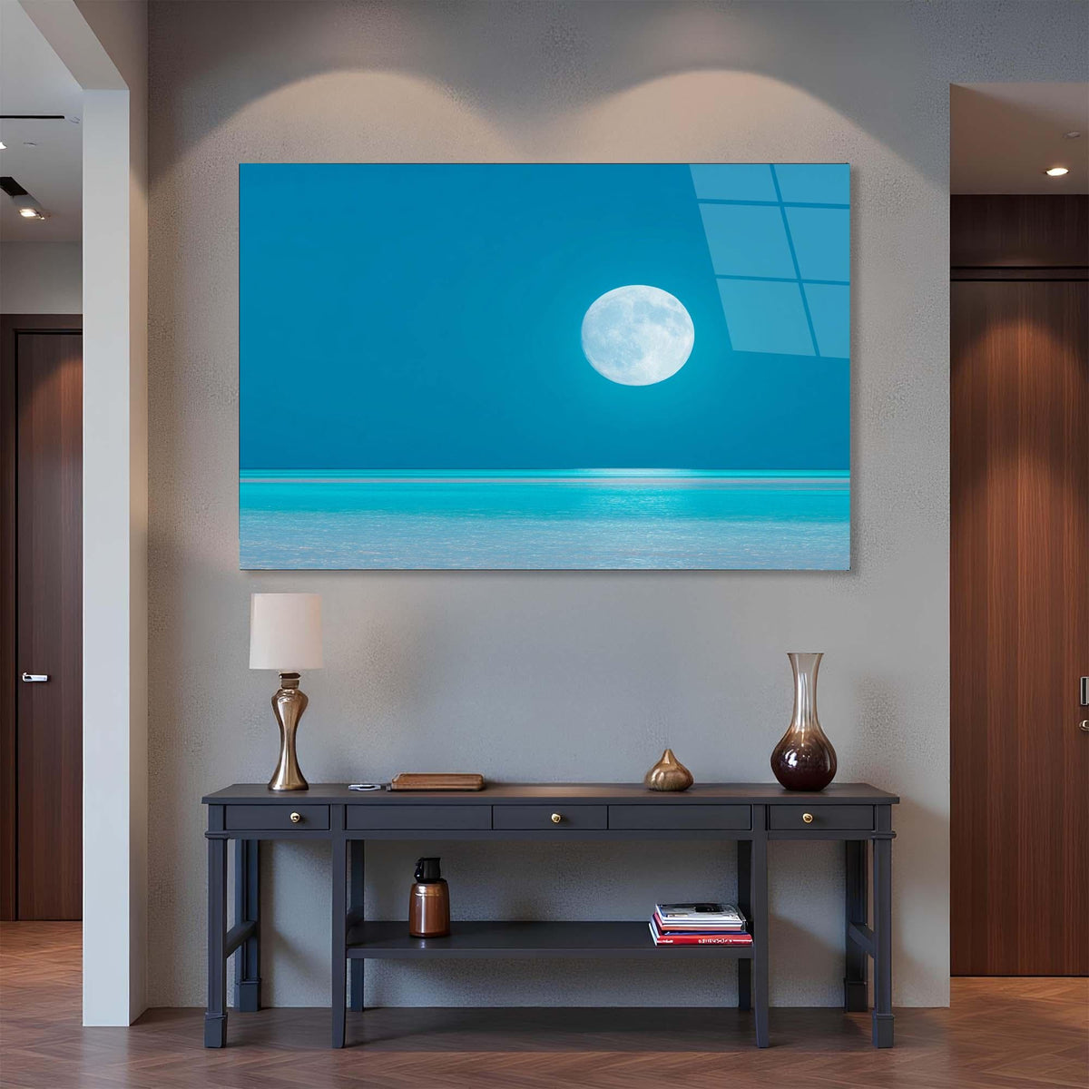Modern interior with a large wall art piece of a moon over water, a console table with decorative items, and a lamp.