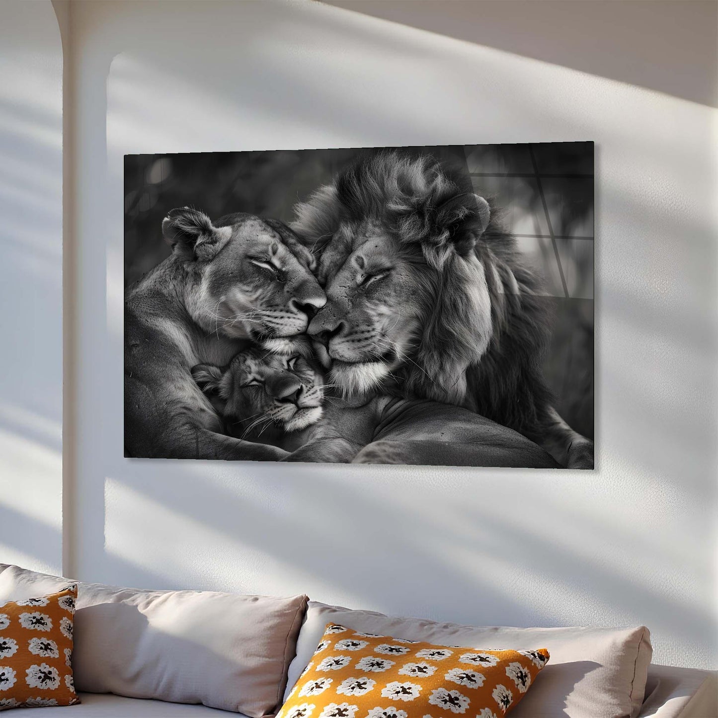 Black and white photo of a lion family on a wall above a sofa with patterned cushions.