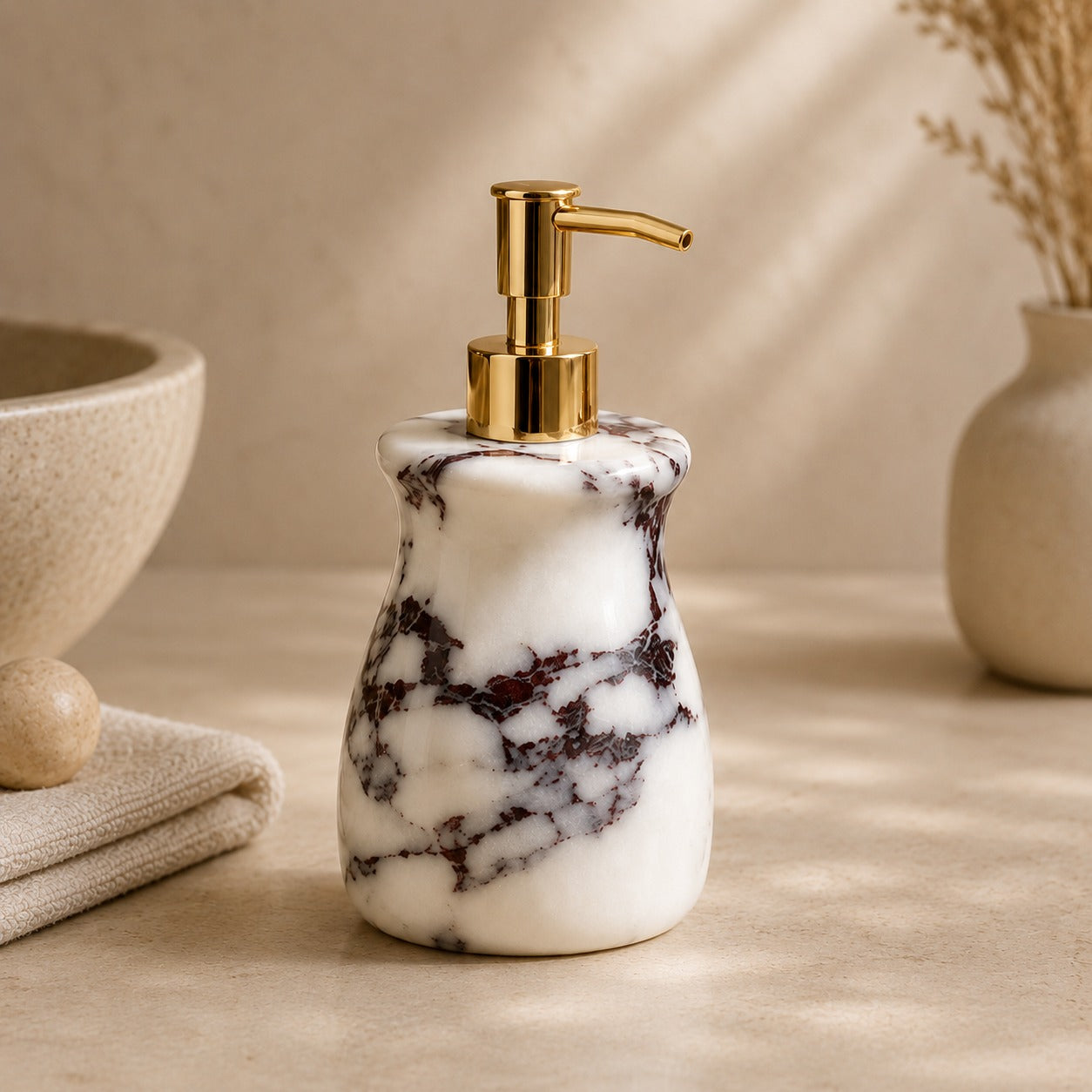 A marble soap dispenser with a white and dark gray veined pattern and a shiny gold pump, set on a beige surface with a neutral background.