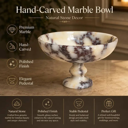 A hand-carved marble pedestal bowl with a cream and dark brown natural stone pattern, shown on a tabletop with promotional text highlighting premium marble, hand-carving, polished finish, and elegant pedestal design.