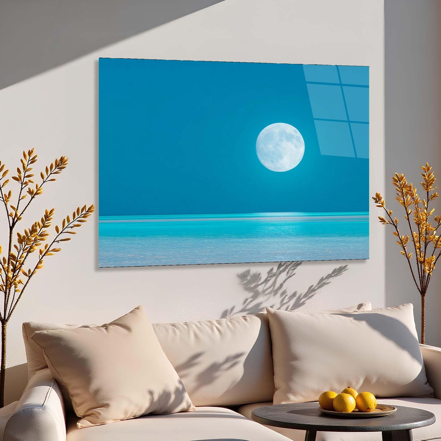Sofa with decorative pillows and a small table with fruits, featuring a large wall art of a beach scene with a moon.