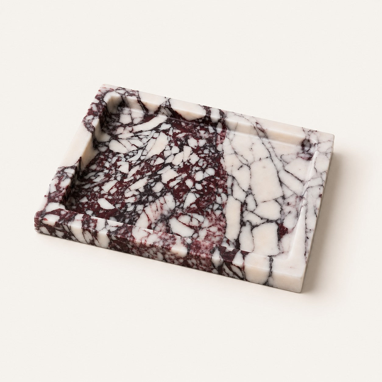 A rectangular marble tray with a raised rim, featuring a marbled pattern of white, deep burgundy, and black veining, photographed on a light cream background.