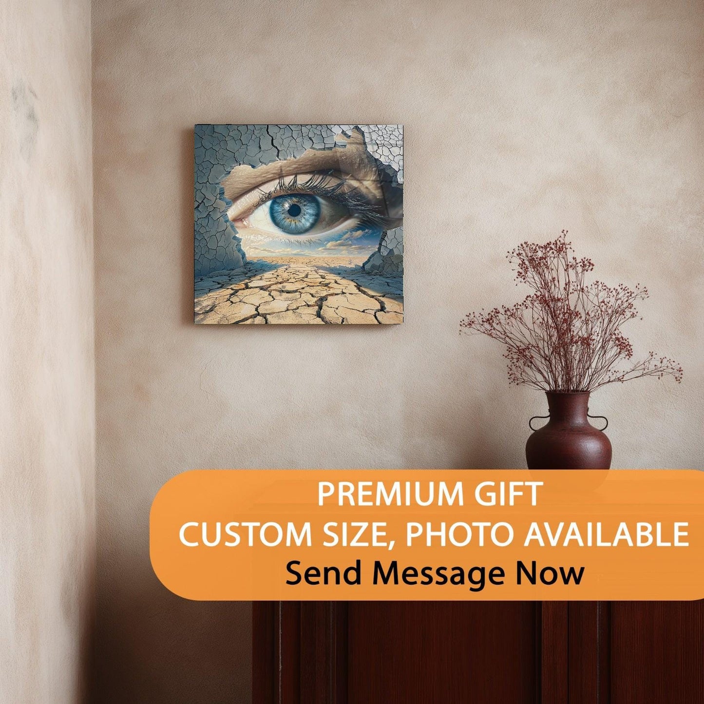 Artistic wall piece with eye and cracked earth design on a beige wall, with a vase of dried flowers below.