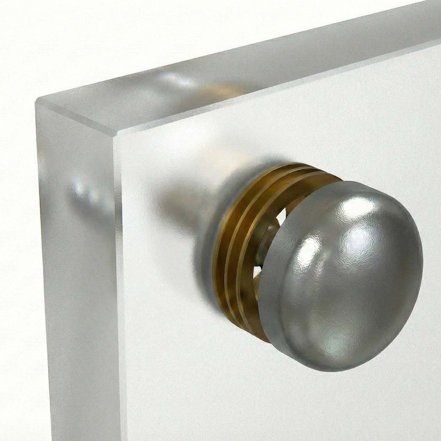 Metallic screw cap on a clear glass backsplash
