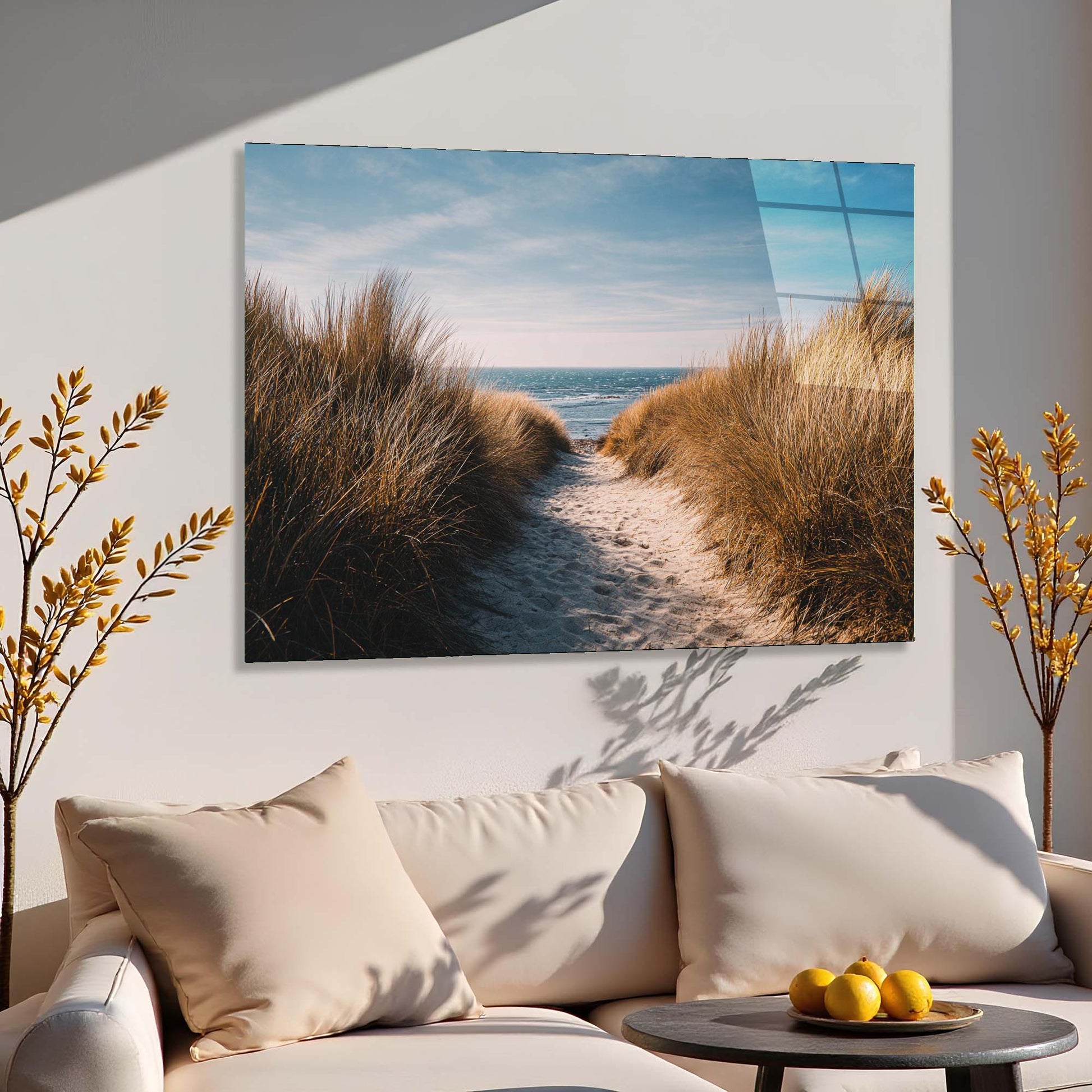Sofa with decorative pillows and a table with fruits, featuring a large wall art of a beach scene.