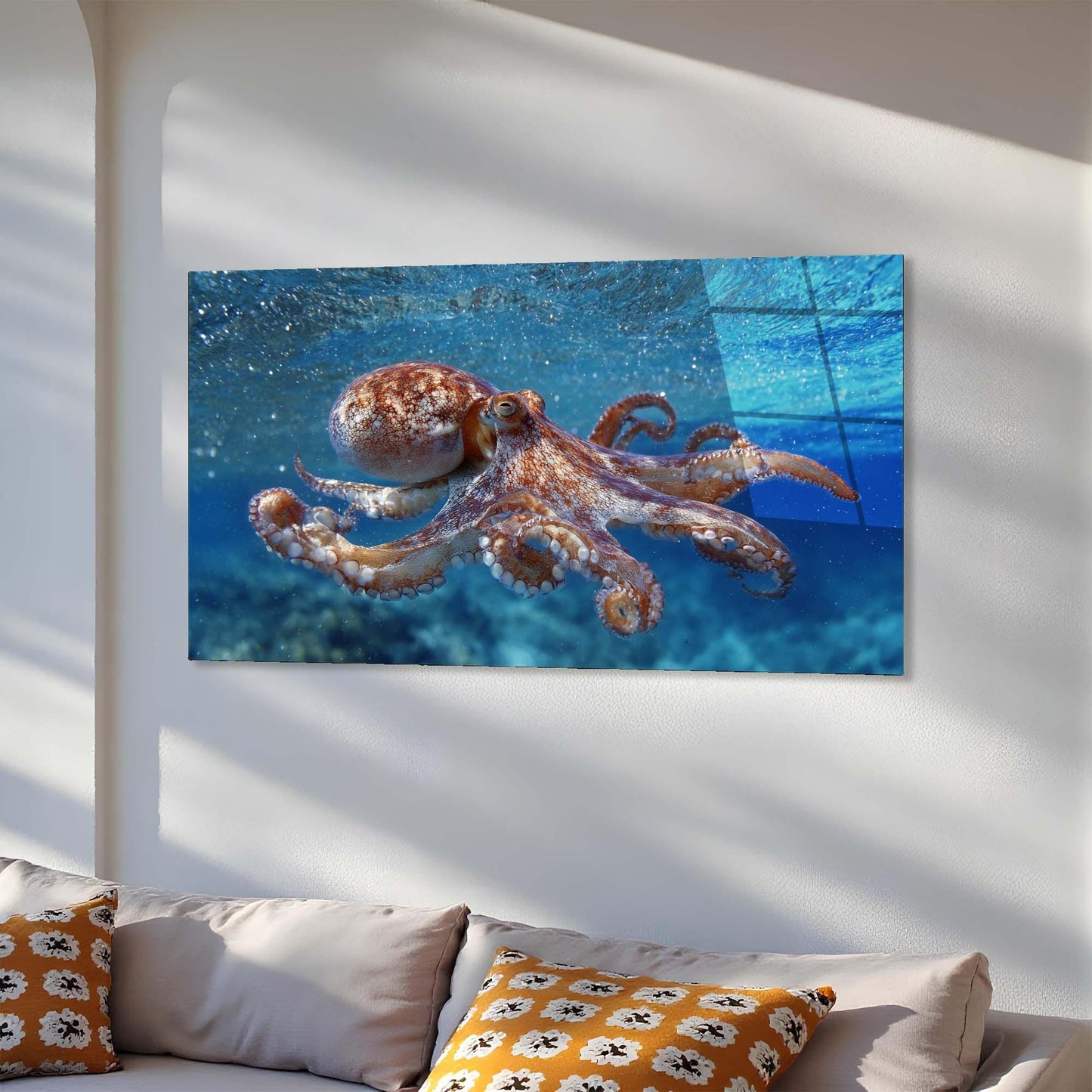Wall art of an octopus underwater on a white wall above a sofa.