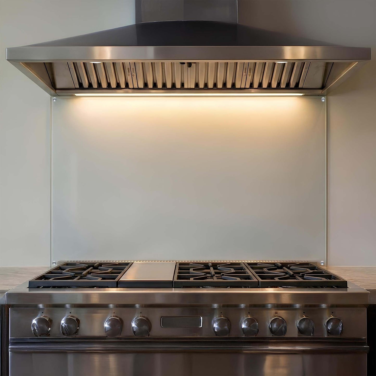 Stainless steel kitchen range with hood, glass backsplash and cooktop