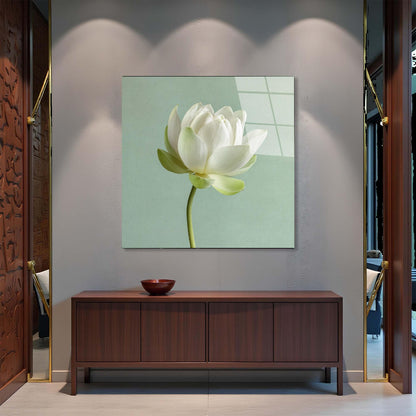 White lotus flower painting on a wall above a wooden cabinet.
