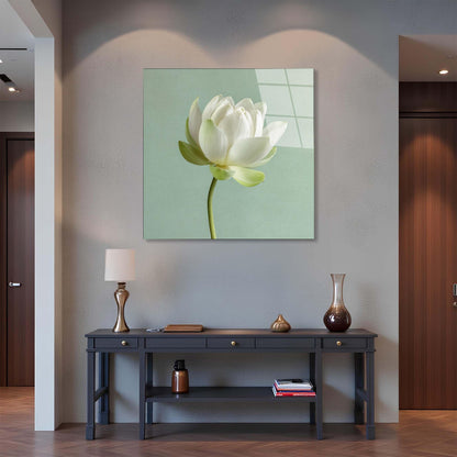 Framed artwork of a white flower on a wall above a dark wooden console table with decorative items.