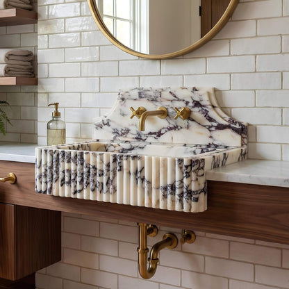 Marble-patterned sink with gold fixtures in a bathroom setting