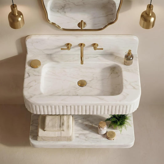 Marble sink with gold fixtures and decorative elements on a neutral background