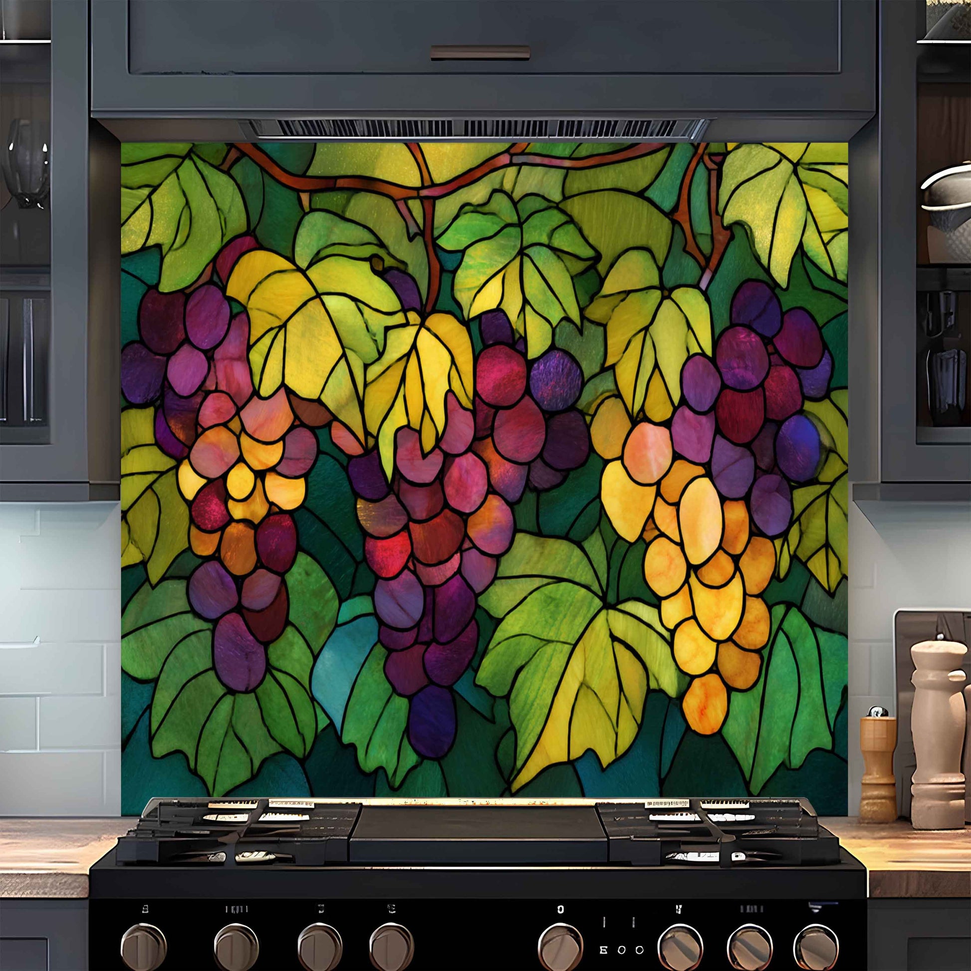 Colorful stained glass-style backsplash of grapes on a kitchen wall above a stove.