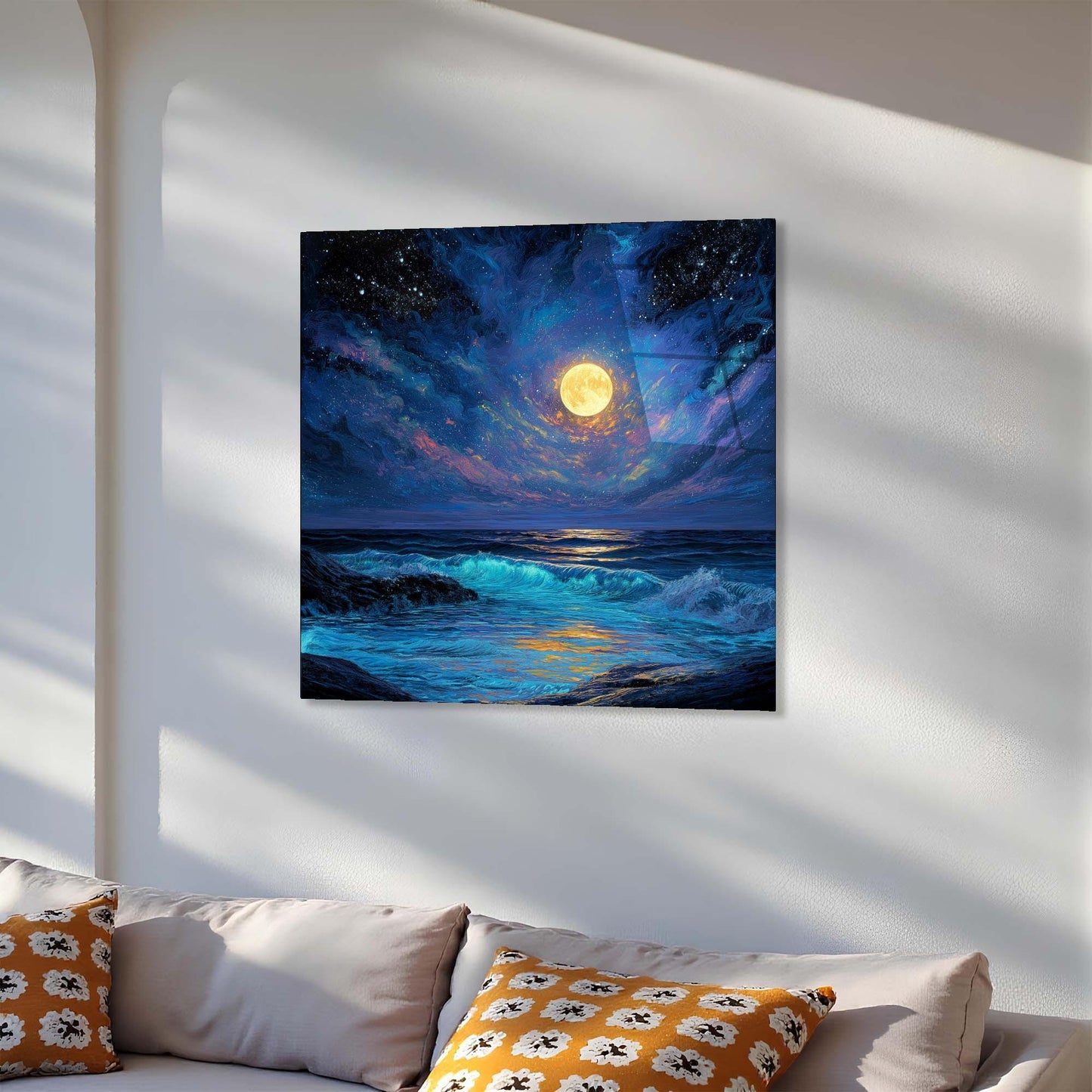 Canvas print of a moonlit sea scene on a white wall above a sofa with patterned cushions.