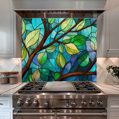 Stainless steel stove with a colorful stained glass-style leaf design on the wall behind it.