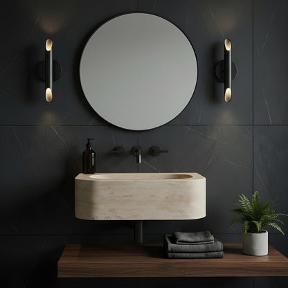 Modern bathroom setup with a round mirror, sink, and decorative elements on a dark tiled wall.