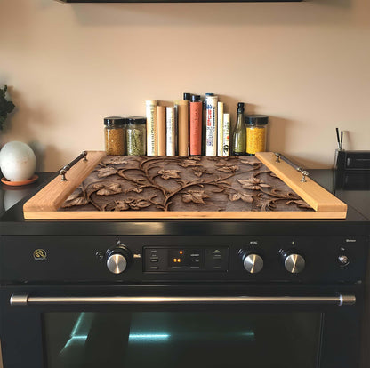 Stovetop with decorative glass cover and books on a kitchen counter.