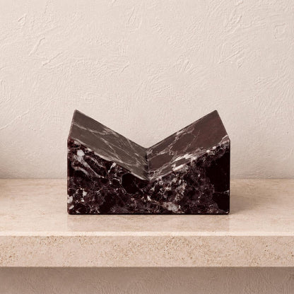 Rosso Levanto marble book stand with deep burgundy veining on a light shelf.