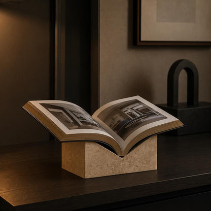 Travertine book stand holding an open book in a warm modern interior.