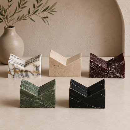 Seven handmade marble and travertine book stands displayed together in natural stone options.