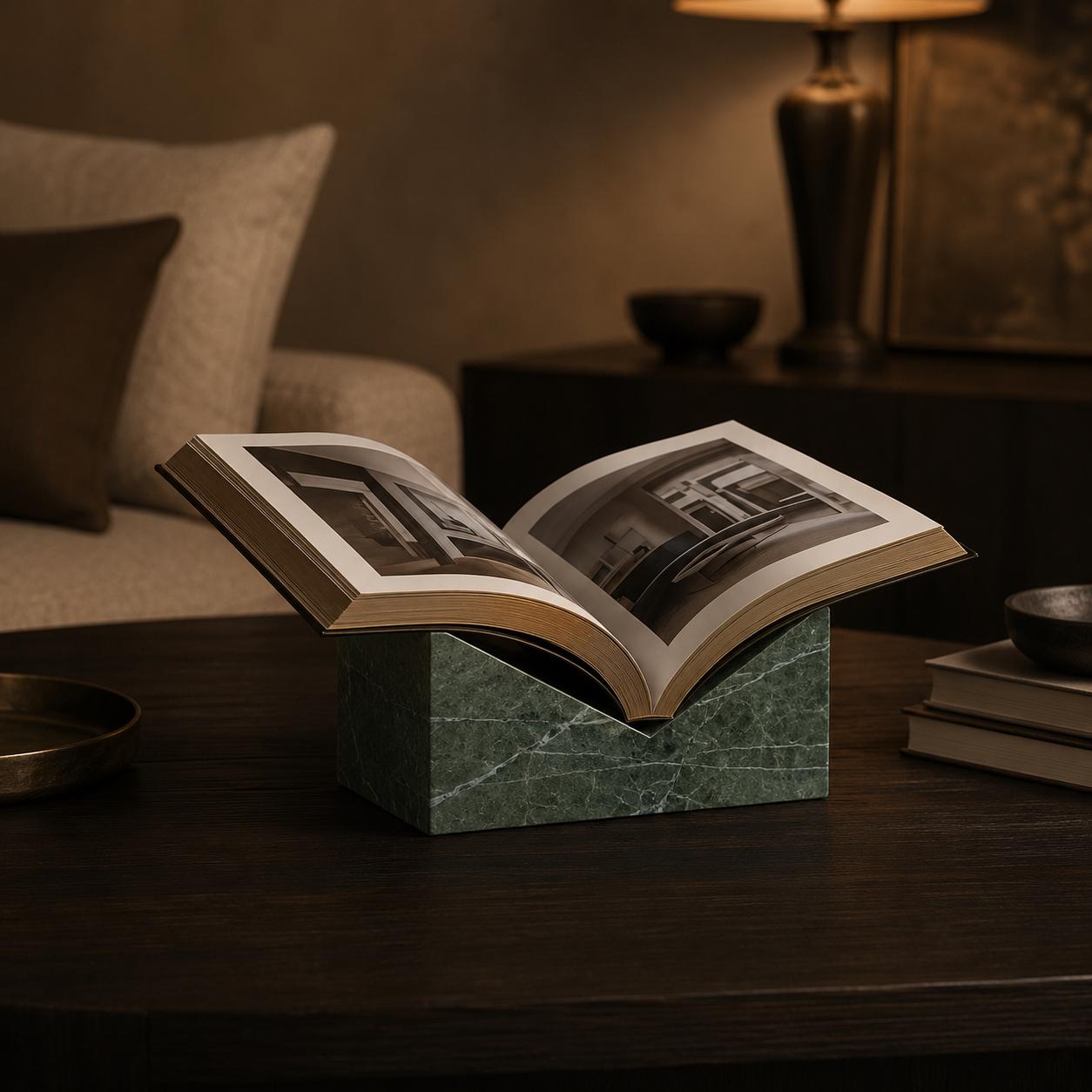 Green Levanto marble book stand holding an open art book in a dark luxury interior.