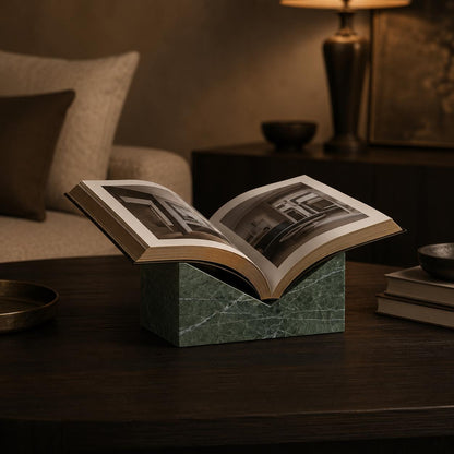 Green Levanto marble book stand holding an open art book in a dark luxury interior.