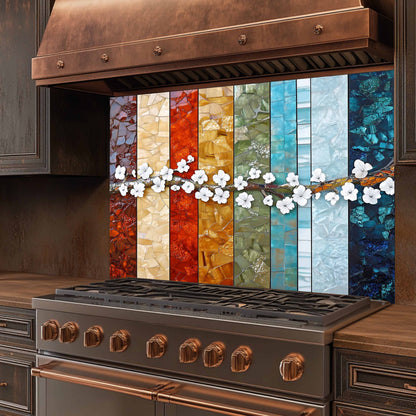 Stainless steel stove with copper accents and a colorful glass backsplash.