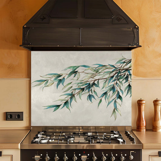 Kitchen with a decorative glass backsplash featuring green leafy branches.
