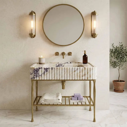 Bathroom vanity with marble sink, round mirror, and wall lights.