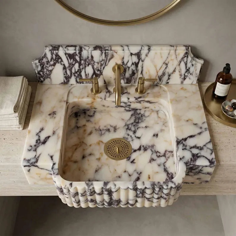 Marble sink with gold fixtures in a bathroom setting