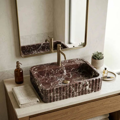 This is not a standard sink. It is a hand-carved dark marble fluted sink, sculpted from a single block of natural stone and designed as a seamless integrated sink and countertop.