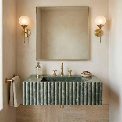 Bathroom vanity with green marble countertop, gold fixtures, and wall lights.