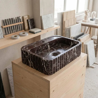 Marble sink on a wooden stand with stone samples in the background