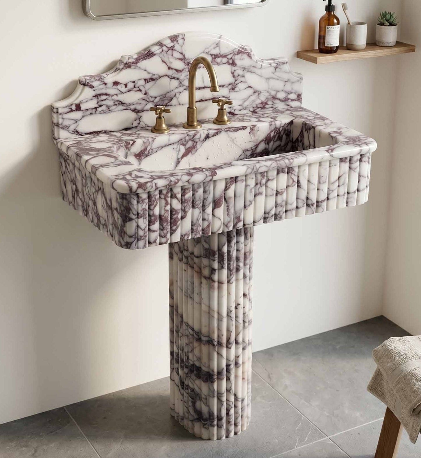 Marble pedestal sink with gold faucet in a bathroom setting