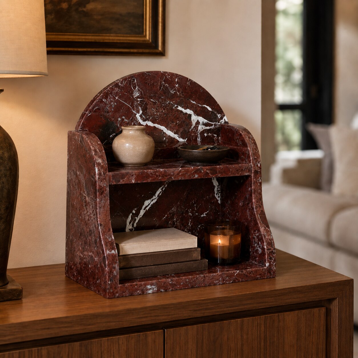 A red marble decorative shelf with a curved backrest, styled on a wooden console table in a warm living room setting.