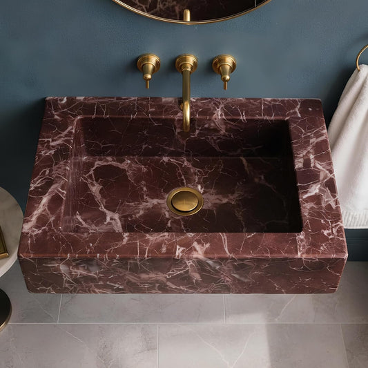 Marble sink with gold fixtures against a blue wall