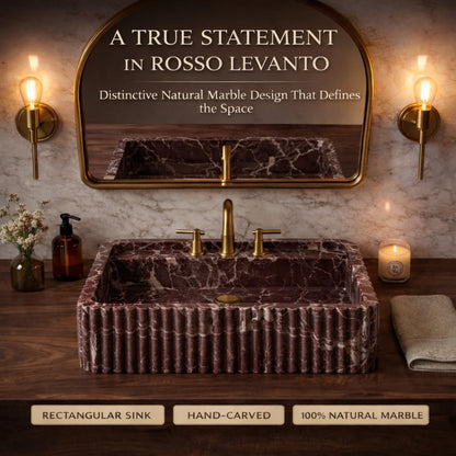 Marble sink with gold fixtures in a bathroom setting, featuring text about Rosso Levanto marble.