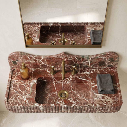 Marble sink with gold fixtures and a mirror in a bathroom setting