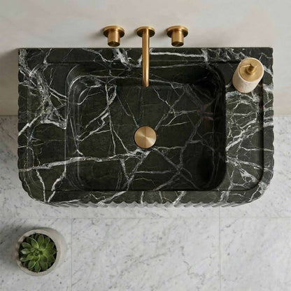 Marble sink with gold fixtures on a white countertop