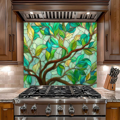 Stainless steel gas stove with decorative glass panel featuring a tree design in a kitchen setting.