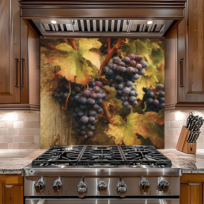 Stainless steel gas stove with decorative glass backsplash of grapes and leaves in a kitchen setting.