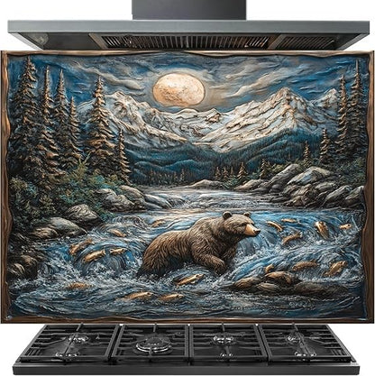 A large decorative wall art panel depicting a mountain landscape at night with a full moon, snowy peaks, pine trees, a bear in a river, and fish, shown installed above a black gas range hood and cooktop.
