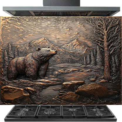 A large decorative wall or range hood panel featuring a raised outdoor landscape scene with a bear, mountains, trees, and rocks in a bronze-like finish, shown installed above a gas stove.