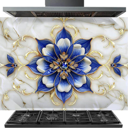 A decorative kitchen backsplash panel featuring a large blue and white floral mandala design with gold accents over a white marble-look background, shown installed above black gas stovetops and under a range hood.