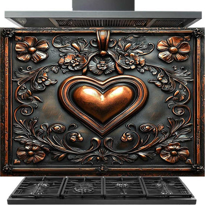 A decorative freestanding cooktop or range hood unit with a large embossed heart motif and floral scrollwork in a dark metallic finish. The front has a central raised copper-toned heart surrounded by floral and vine details, with black grates visible along the bottom and a dark metallic top section above.