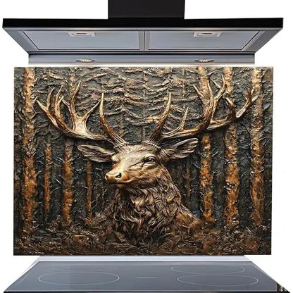 A decorative kitchen backsplash panel featuring a highly detailed, textured 3D-style relief of a stag deer head with large antlers in front of a forest background. The panel is shown installed on a modern black induction cooktop with a matching black range hood above, set against a plain white background.
