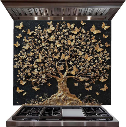 A large decorative wall panel or backsplash featuring a raised tree of life design with metallic gold leaves and butterflies on a black background, installed above a stainless steel gas range hood and cooktop.