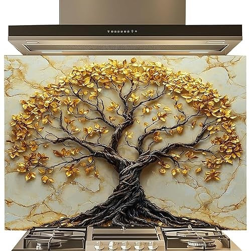 A decorative kitchen backsplash tile featuring a large 3D-style tree of life with gold metallic leaves and a dark brown trunk, set against a beige marble-look background. Stainless steel range hood and gas stovetop are shown above and below the tile.