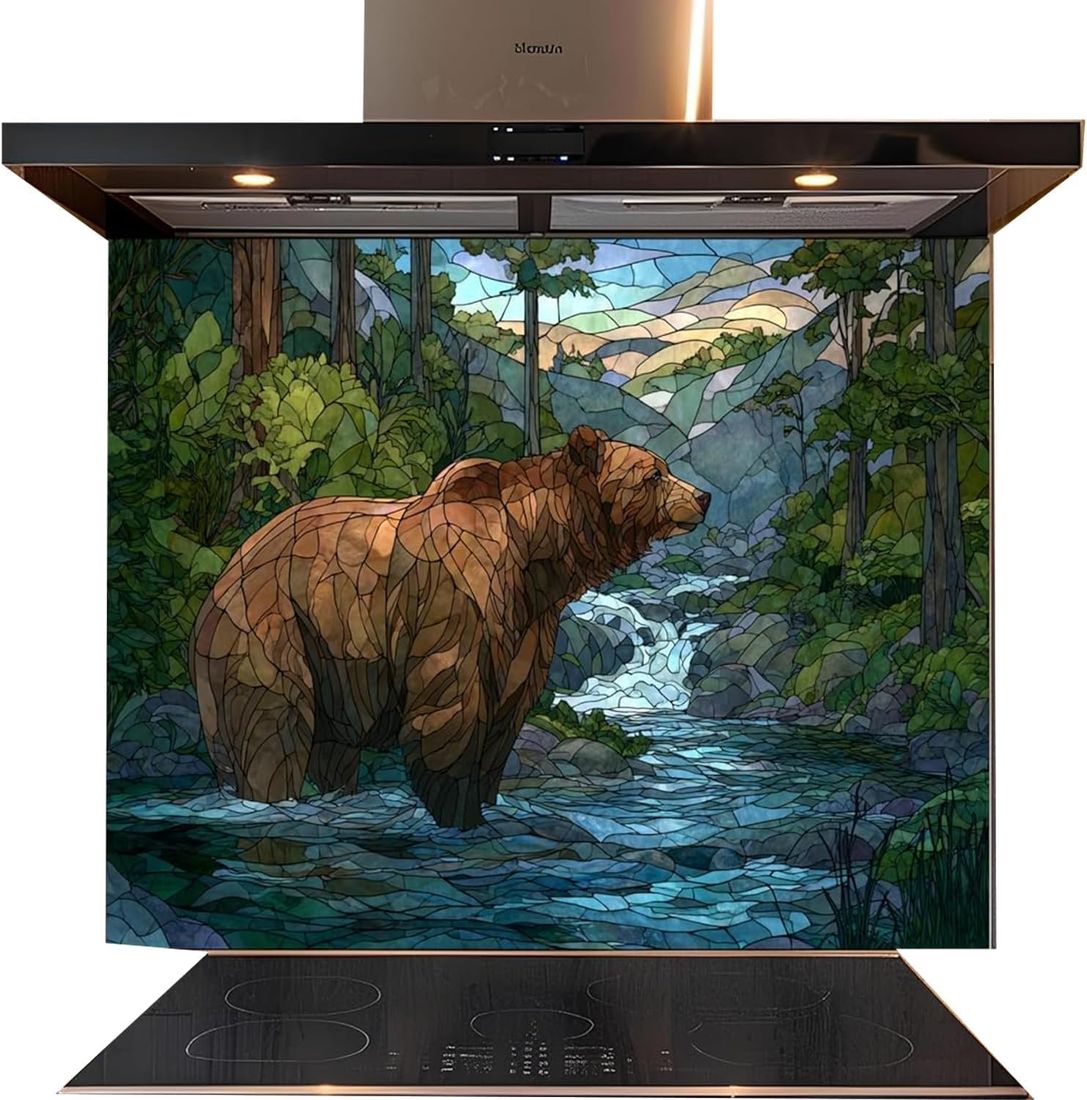 A kitchen backsplash panel featuring a stained-glass-style illustration of a brown grizzly bear standing in a blue stream surrounded by green trees and mountains. The panel is installed on a black induction range hood and cooktop against a white background.